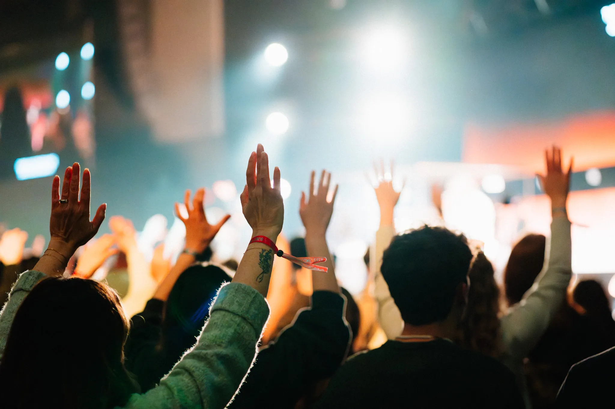 Black and white photo of hands laid on a man's shoulders in prayer during a worship service.