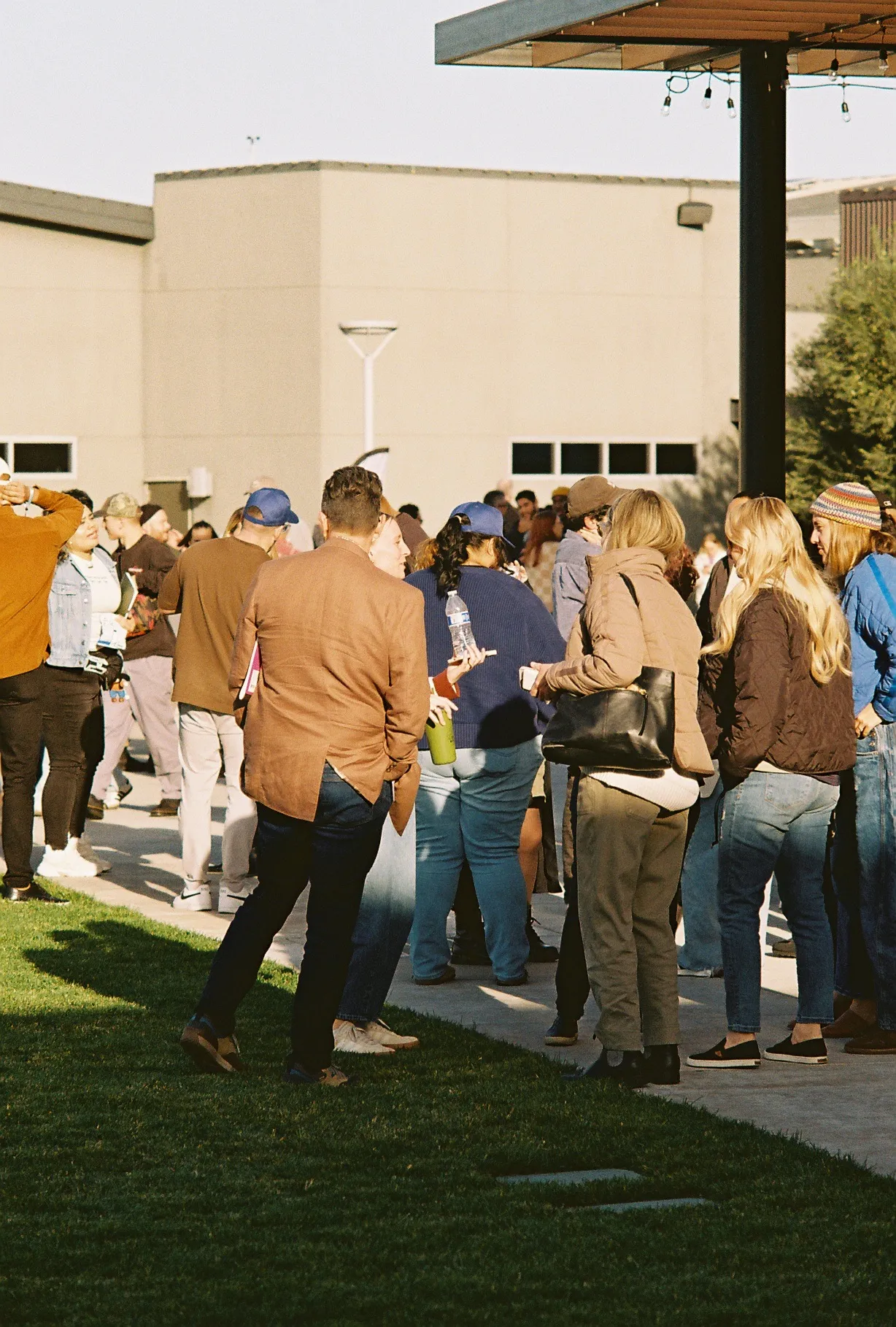 A film photo of a crowd with hands raised under warm and blue stage lighting.