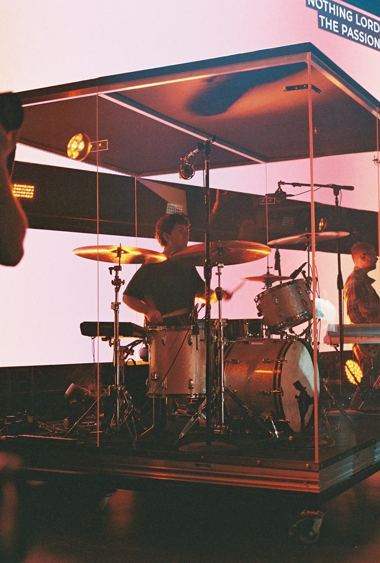 A film photo of a man playing electric guitar on stage with another guitarist visible behind him.